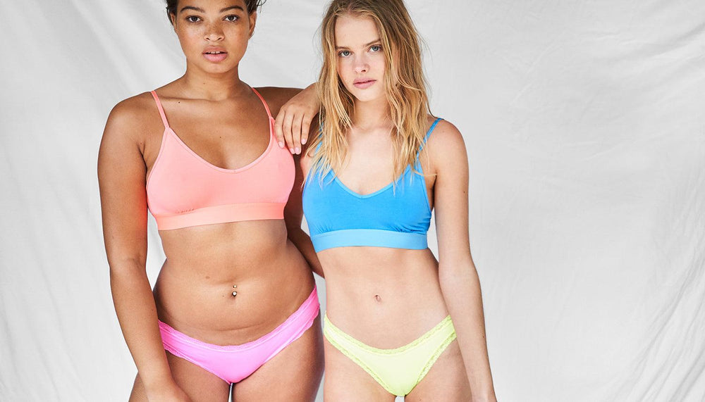 Two models posing in a studio wearing neon underwear sets
