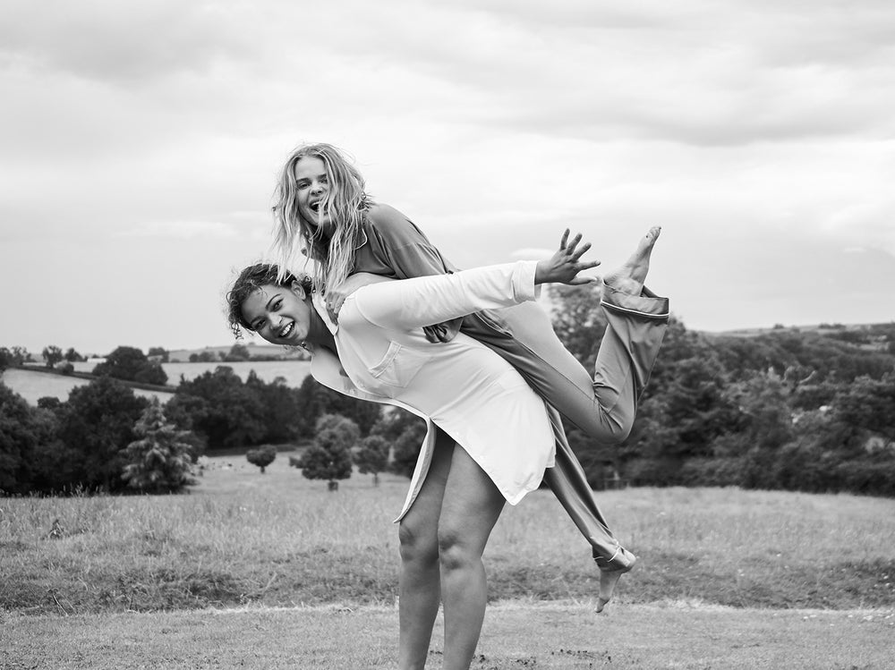 Two models playing around in a field wearing pyjamas