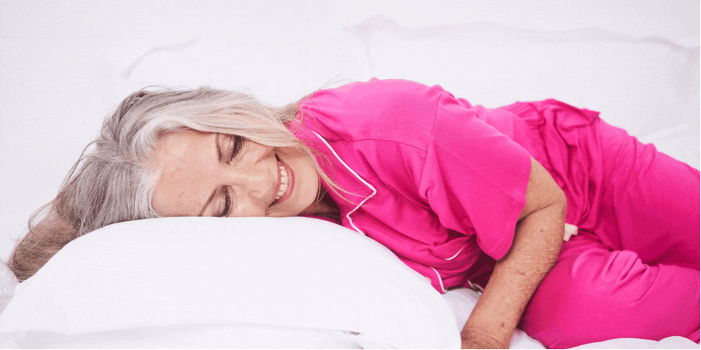 woman lying on bed in pink pajamas