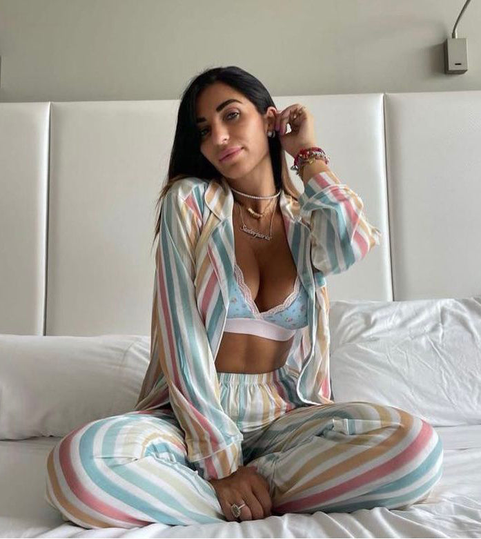 Woman sat on her bed wearing striped pyjama set