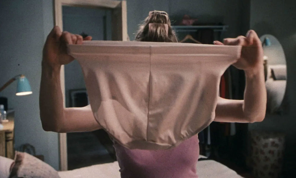 Bridget Jones holding up a pair of beige support pants